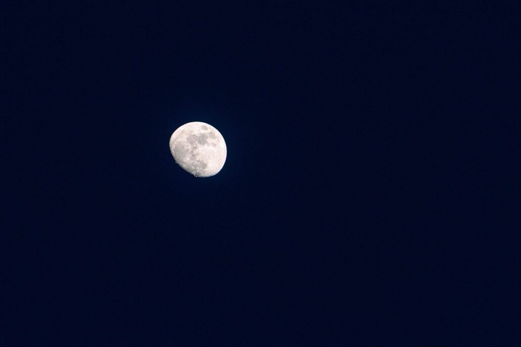 A nearly full moon hangs in a clear navy sky over Miyako Island at the end of the wedding day, its craters soft grey against the dark.