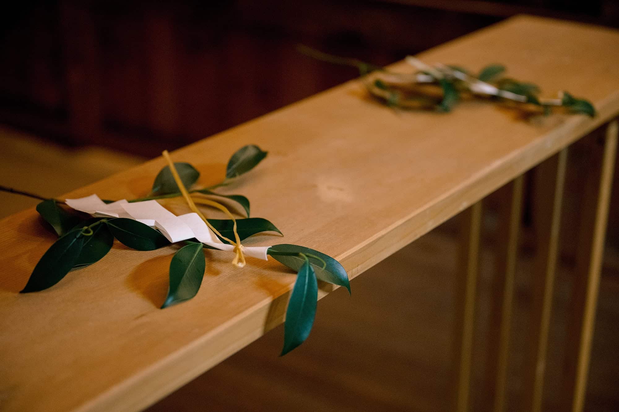 Two sakaki branches tied with white paper rest on a wooden offering rail inside a shrine near Lake Kawaguchiko after a Shinto wedding blessing.