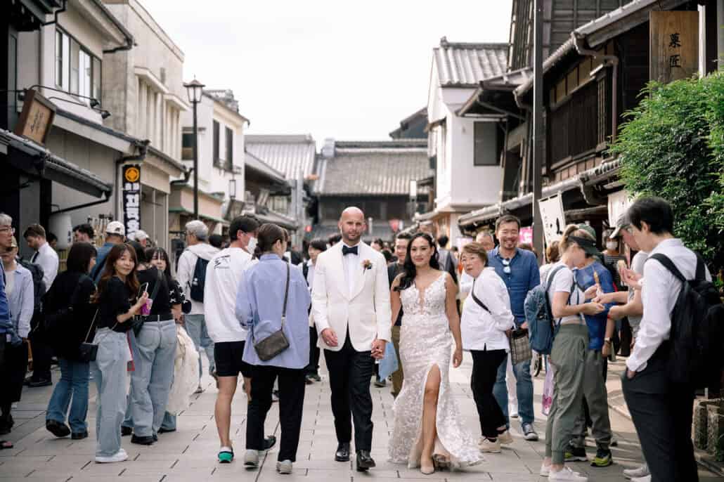 Visitors turn to watch as the bride and groom walk up the old street of Kawagoe's kurazukuri town hand in hand.
