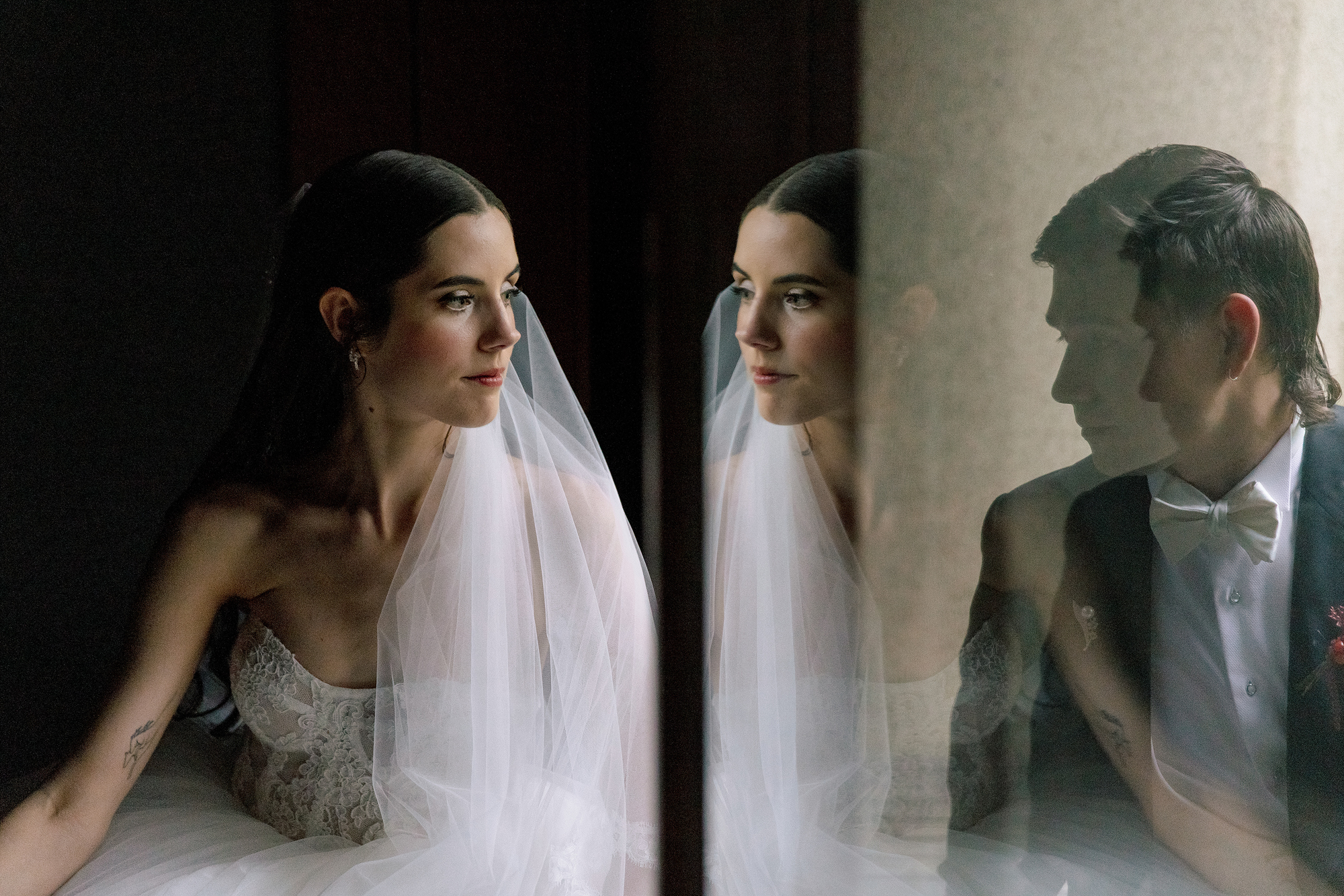 The bride by a window at Jinya, the groom reflected in the glass beside her, a portrait on their wedding day.