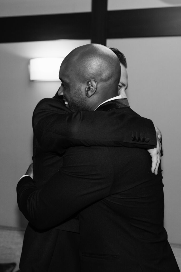 In black and white, a long hug between friends after the ceremony.
