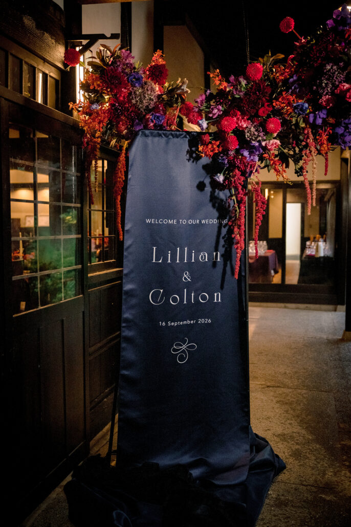 A navy welcome banner hung with deep red flowers at the entrance to the reception.