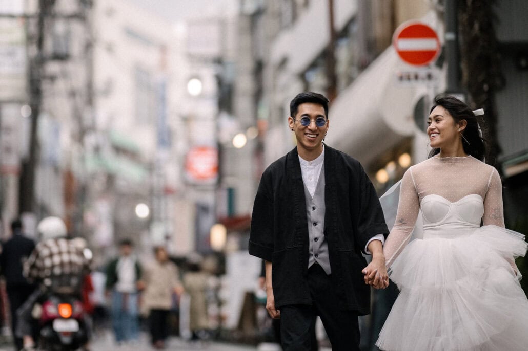 The couple smile at each other on a busy Shimokitazawa shopping street in Tokyo, the kind of street where tax-free shopping in Japan begins.