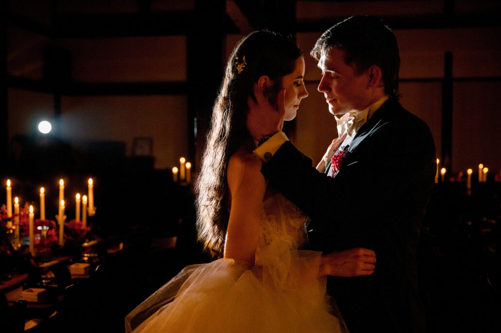 The bride and groom face to face in the candlelight of the reception room.