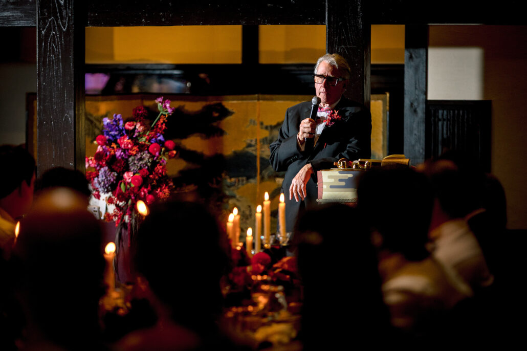 A guest gives a speech at the microphone beside the flowers.