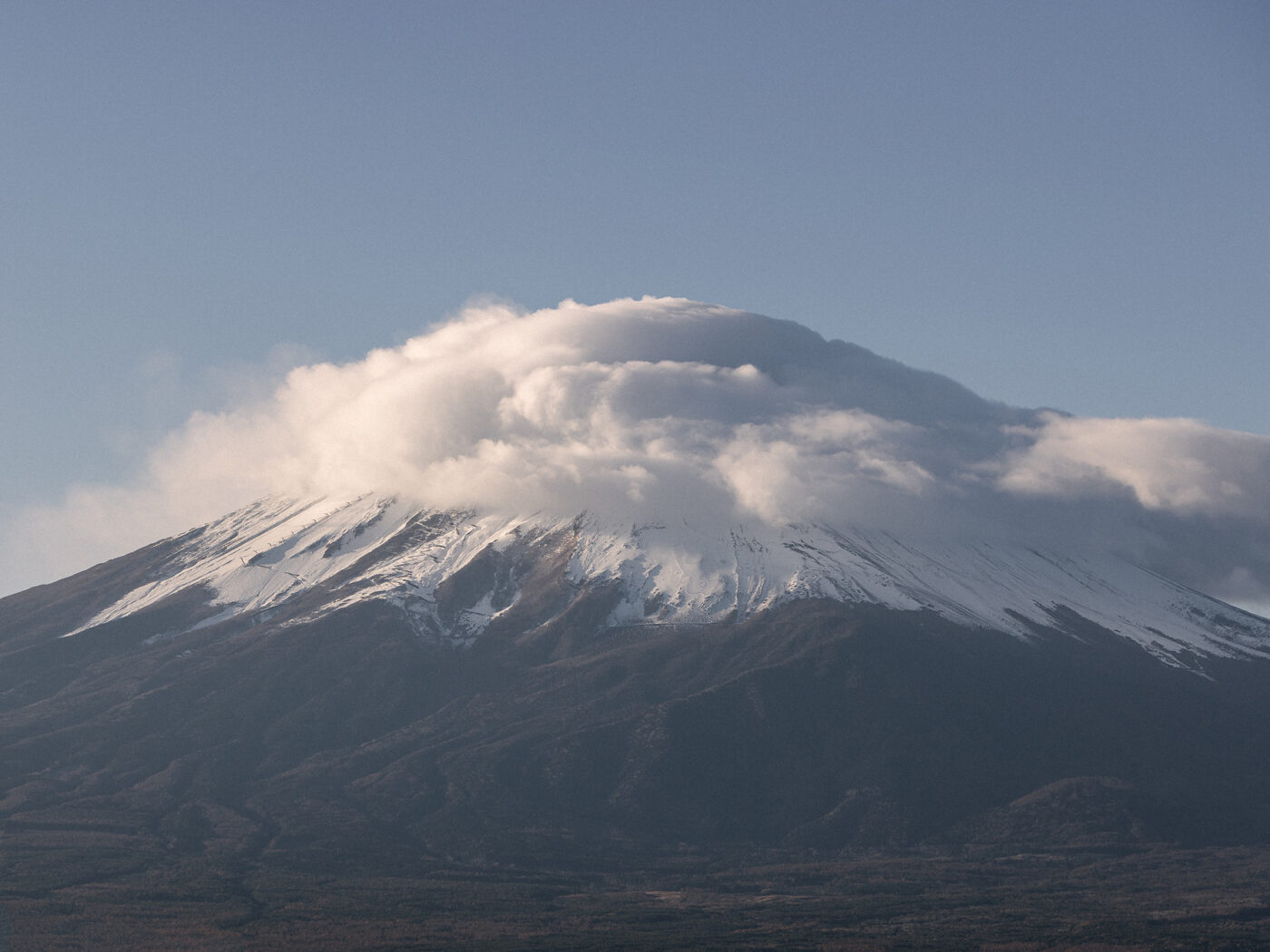 Mt Fuji in early morning light with a kasagumo, a cap cloud made by the wind, sitting over its snowy summit.