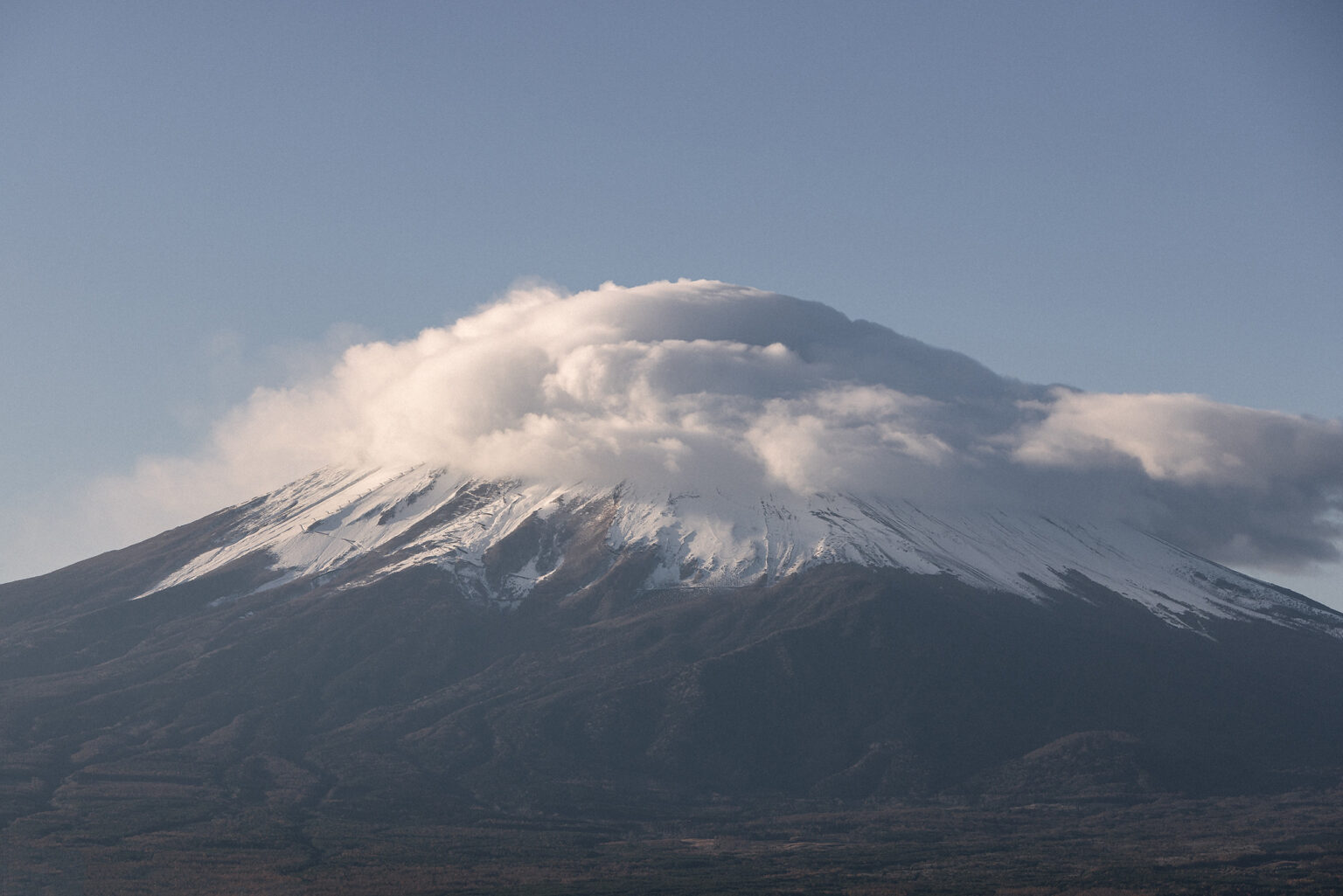 Mt Fuji in early morning light with a kasagumo, a cap cloud made by the wind, sitting over its snowy summit.