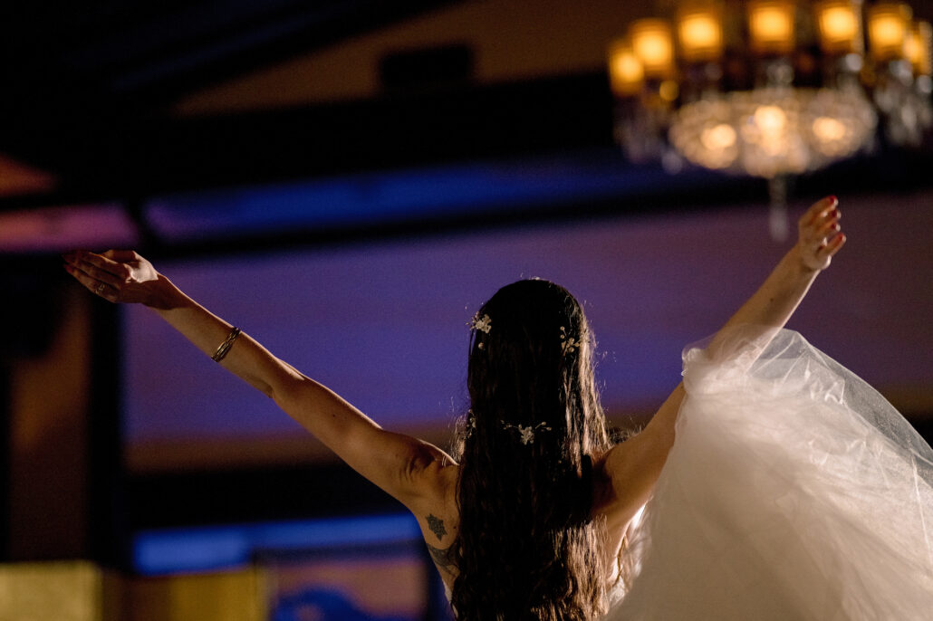 The bride, arms open, mid-turn in her first dance at Jinya.