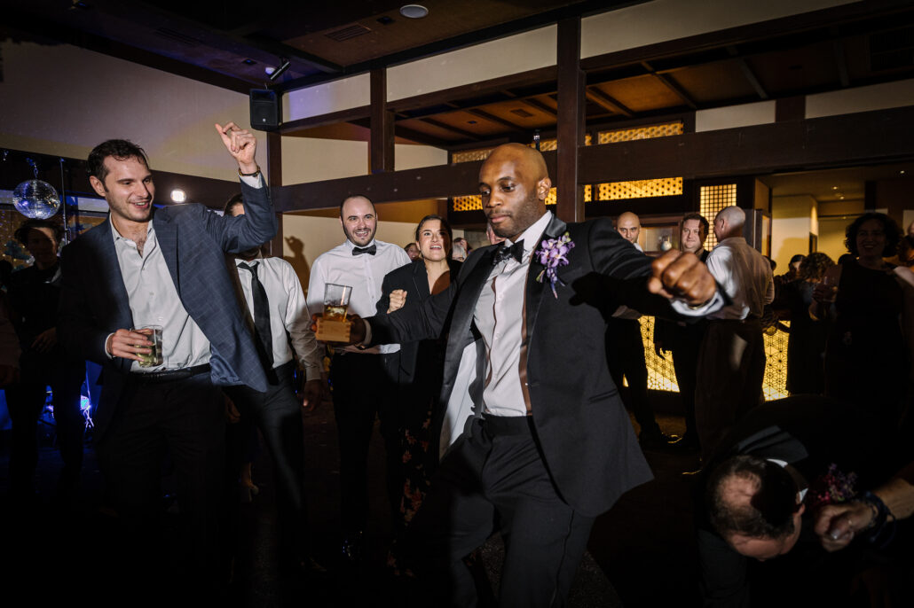 Guests cheer at the edge of the floor with drinks raised at the reception at Jinya.