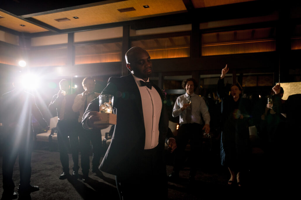 A guest dances at the edge of the floor as a light flares across the reception room.