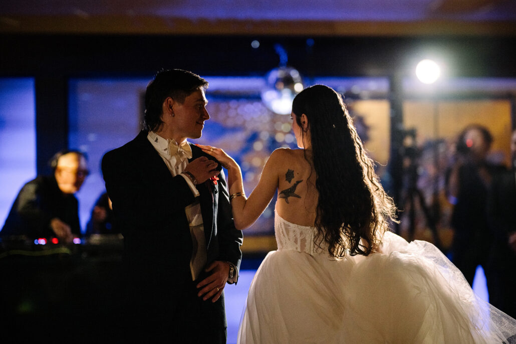 The first dance under blue light, the bride's hand on the groom's shoulder.