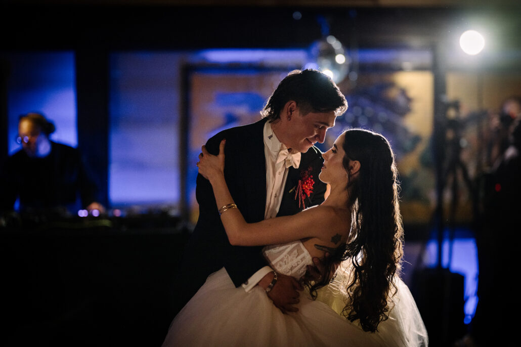 The groom dips the bride under blue light at the end of a turn.