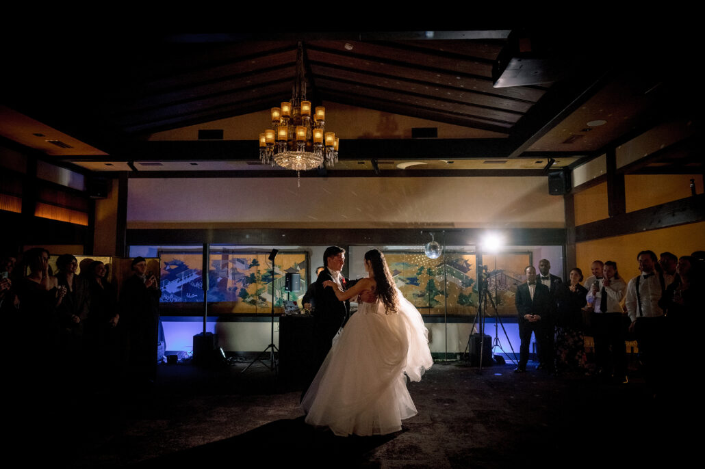 A wide view of the first dance beneath the chandelier, guests watching.