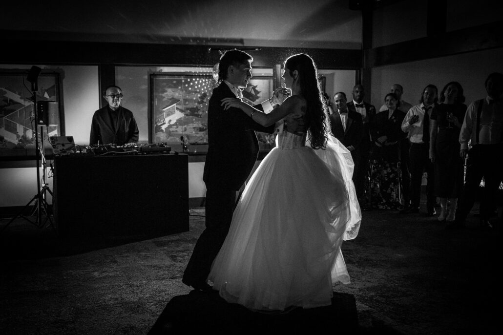 In black and white, the couple waltz with the DJ behind them.