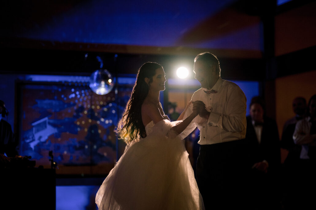 The bride dances with her father under blue light at a ryokan wedding reception in Japan