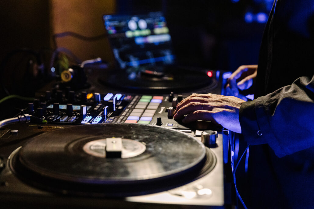 Close on the DJ's hands on the turntable and mixer at the wedding reception.