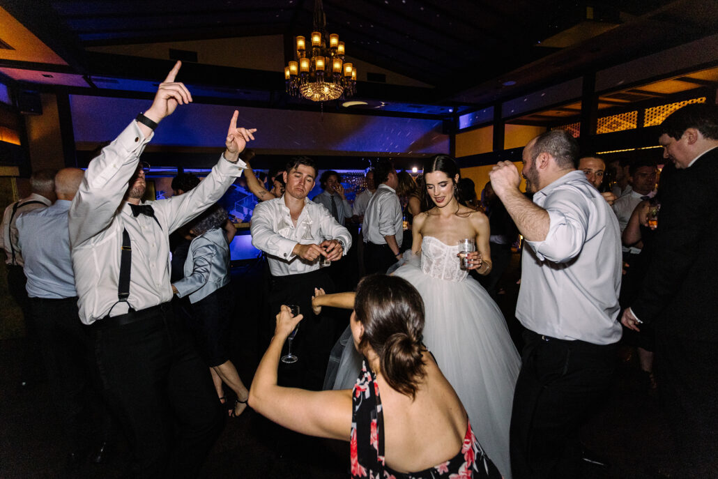 Guests point and cheer on the dance floor around the bride and groom.
