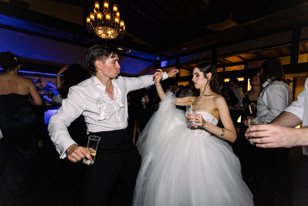 The bride and groom dance among their guests beneath the chandelier at Jinya.