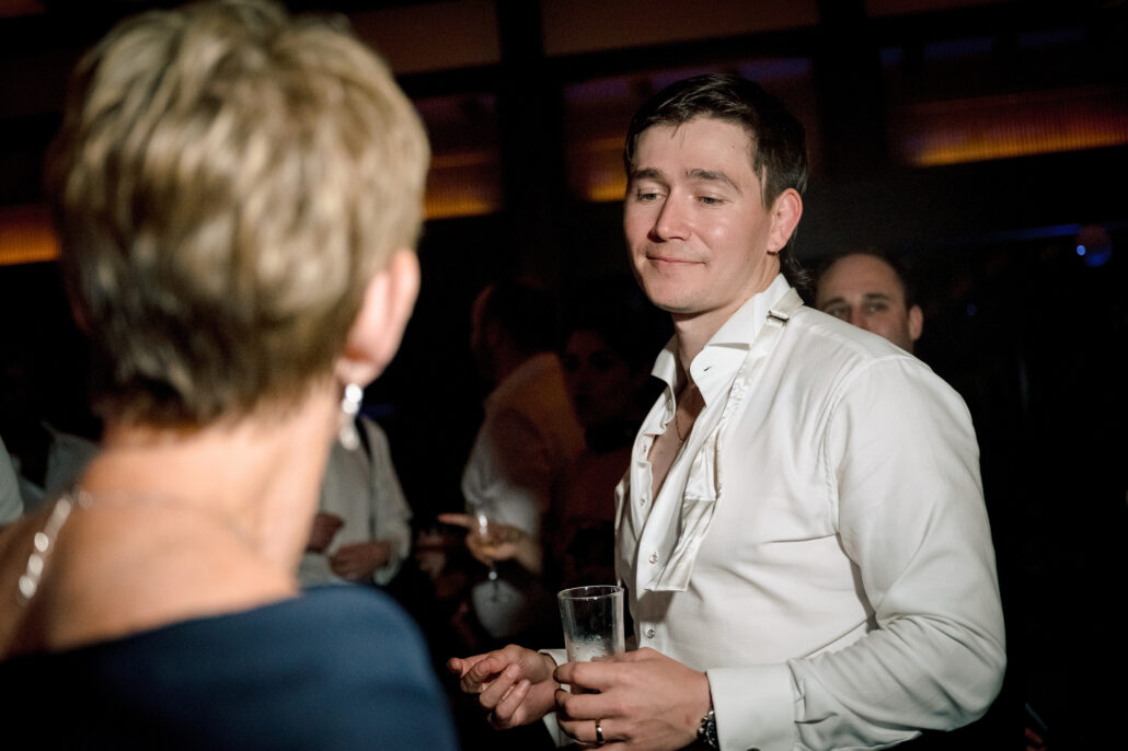 The groom laughs with a guest on the dance floor.