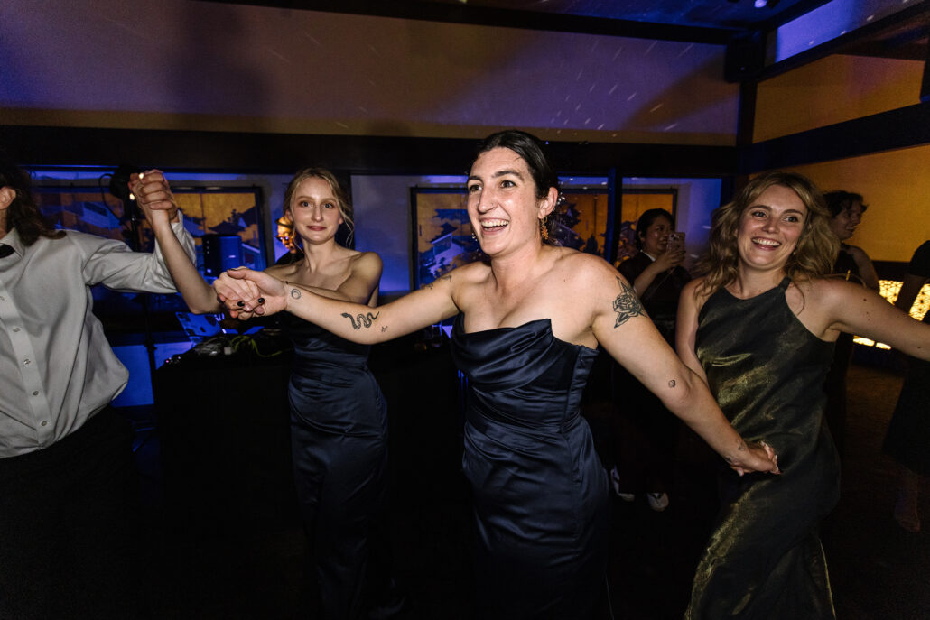 A bridesmaid laughs as the circle dance spins around the room.