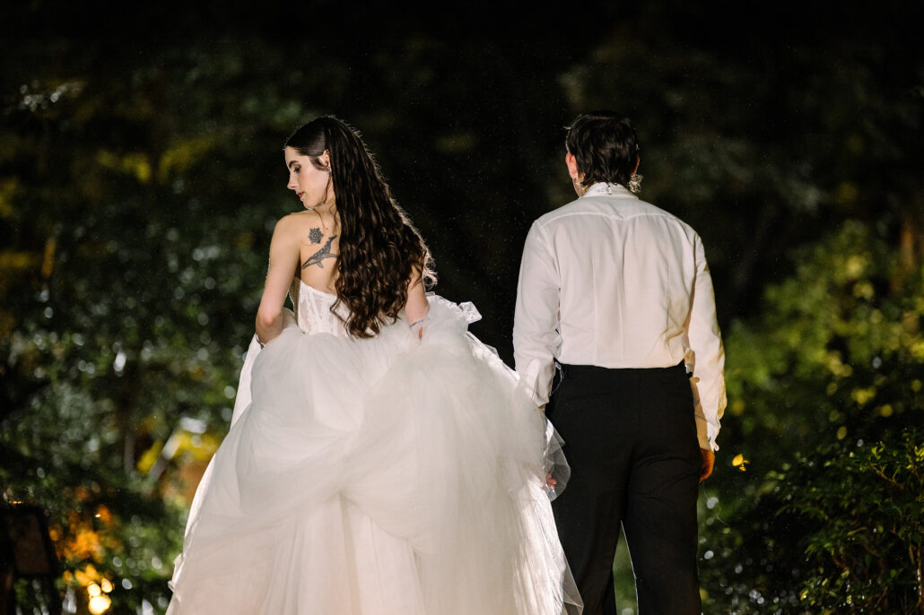 The bride glances back over her shoulder as the couple walk into the night garden at Jinya.