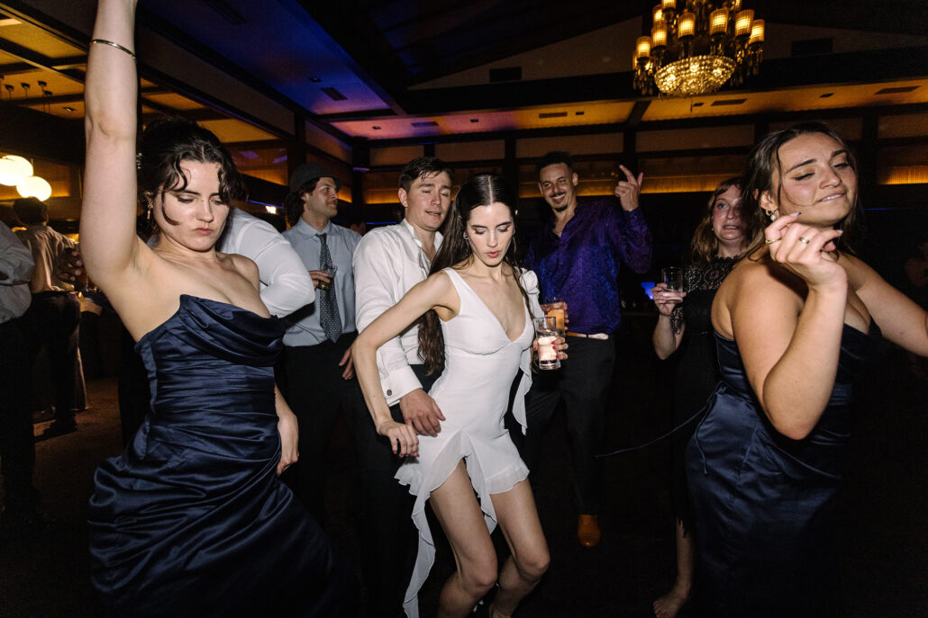The bride, changed into a short white dress, dances with her bridesmaids late at night.