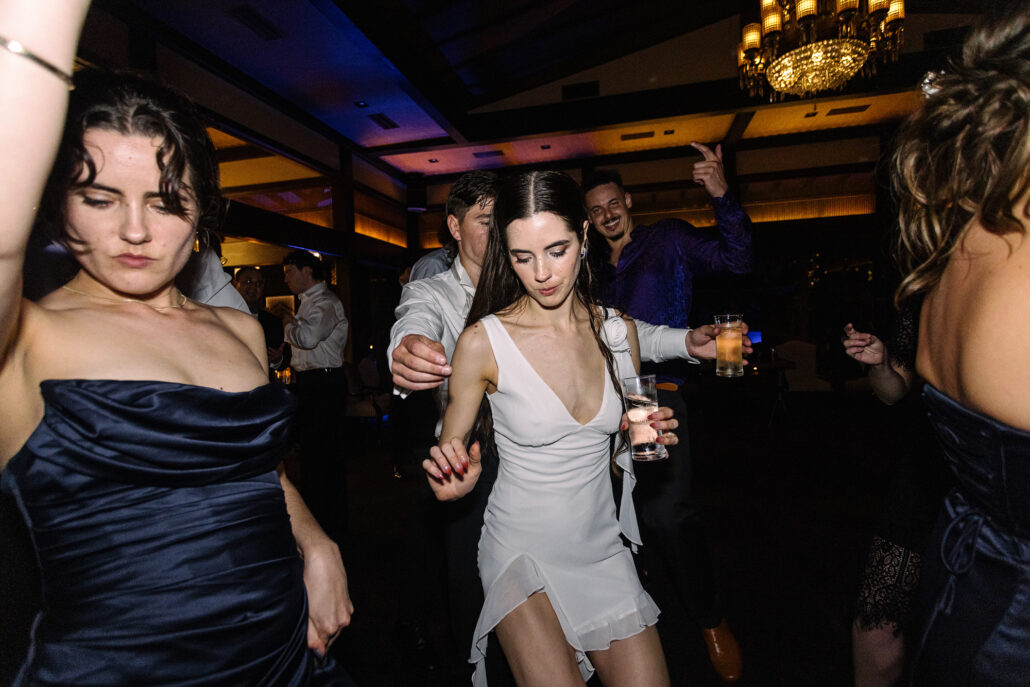 The bride dances in her short dress, a drink in her hand.
