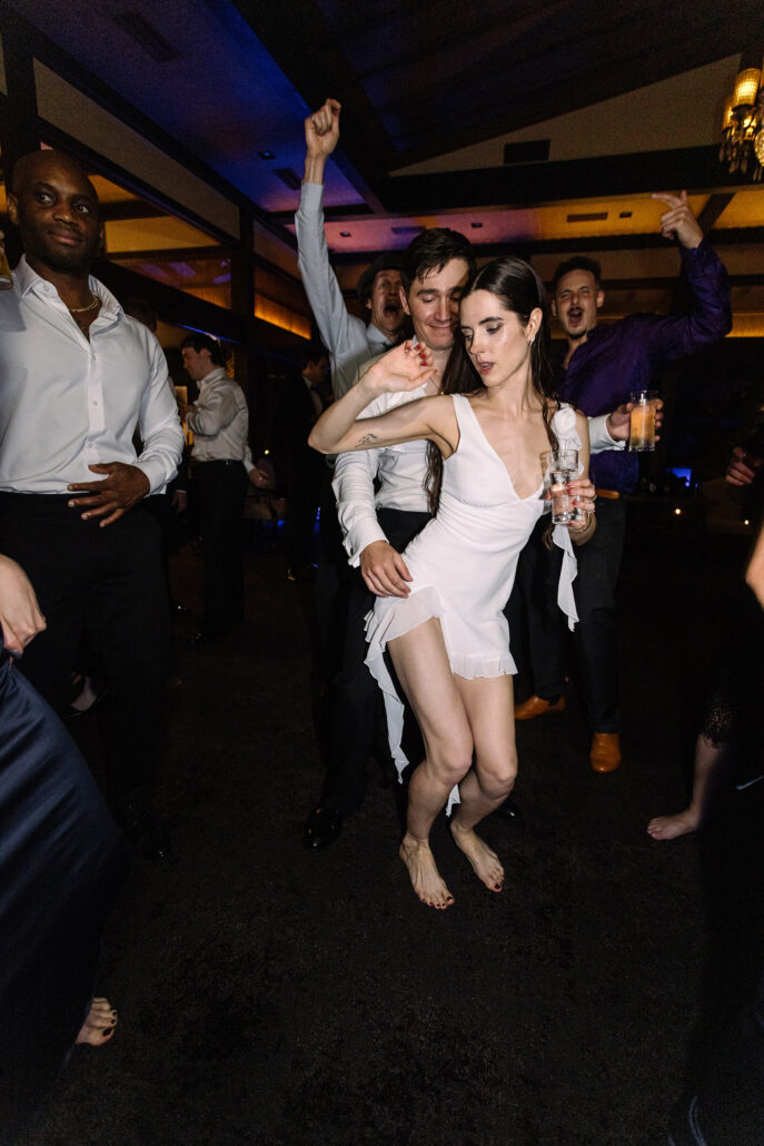 The bride dances in her short white dress among her guests.