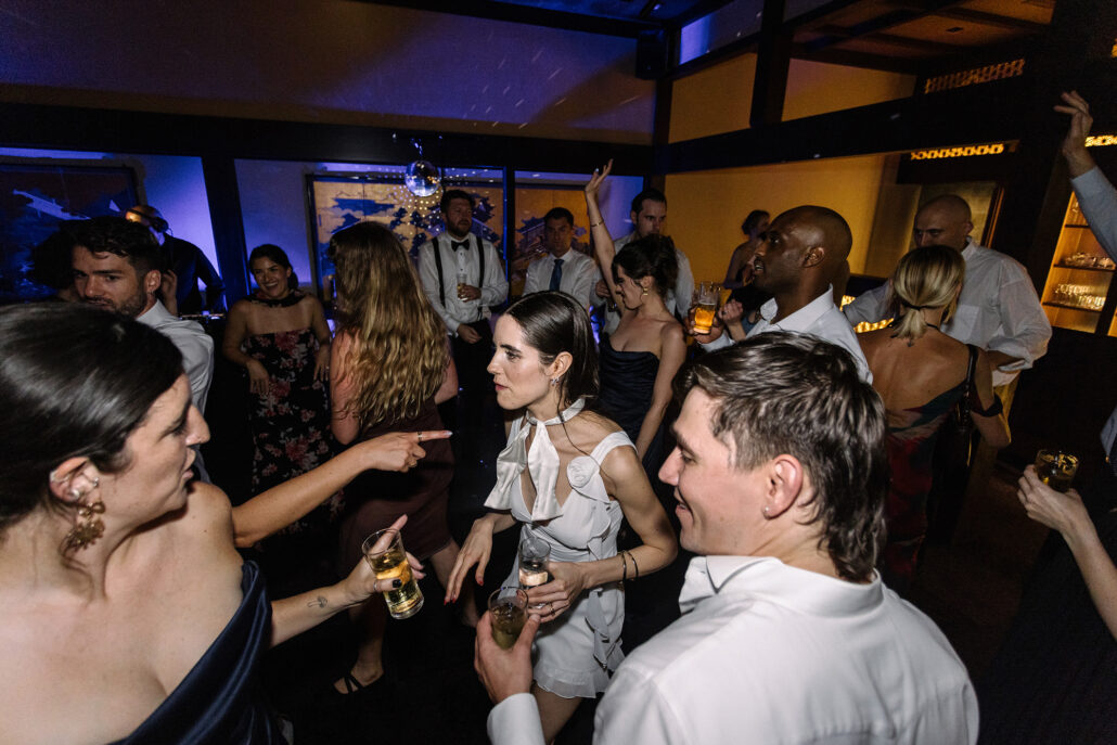 The bride laughs with friends on the dance floor late at night.