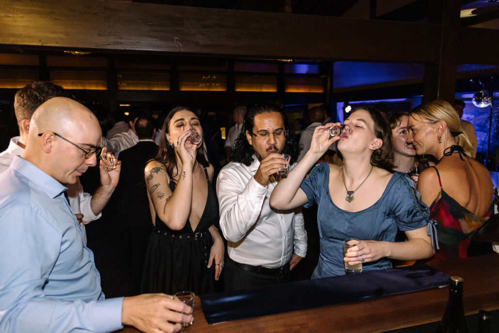 Friends raise their glasses for a round at the bar.