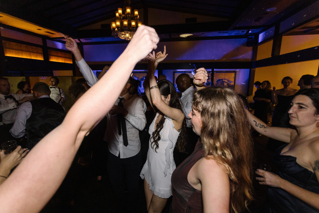 The bride dances in the crowd, an arm raised in the foreground.