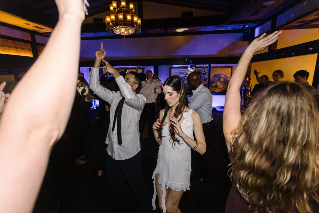 The bride dances as guests throw their arms in the air.
