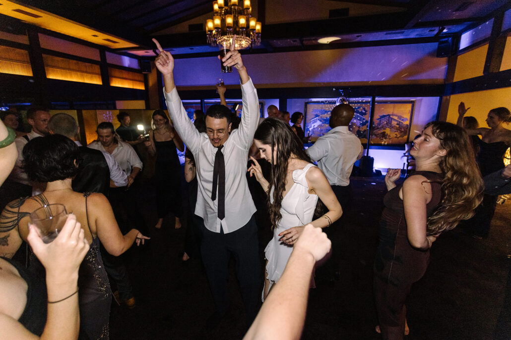 The groom and bride dance with their arms raised at the end of the night.