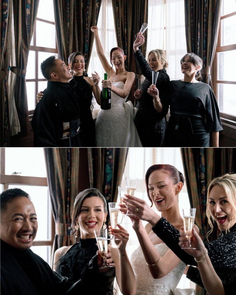 The bride holds a bottle of champagne with one arm raised among friends by the tall chalet windows, then glasses meet in a toast before her Hakuba wedding.