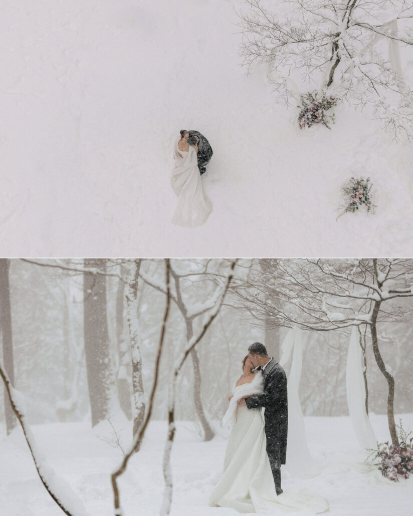 An aerial of the couple small in the snow covered forest, and the bride and groom holding each other among birch trees as snow falls.