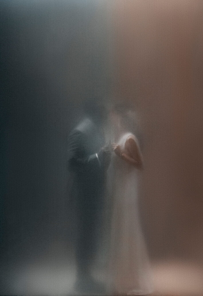 A couple dance, softened as if seen through mist, in shades of blue and rose.