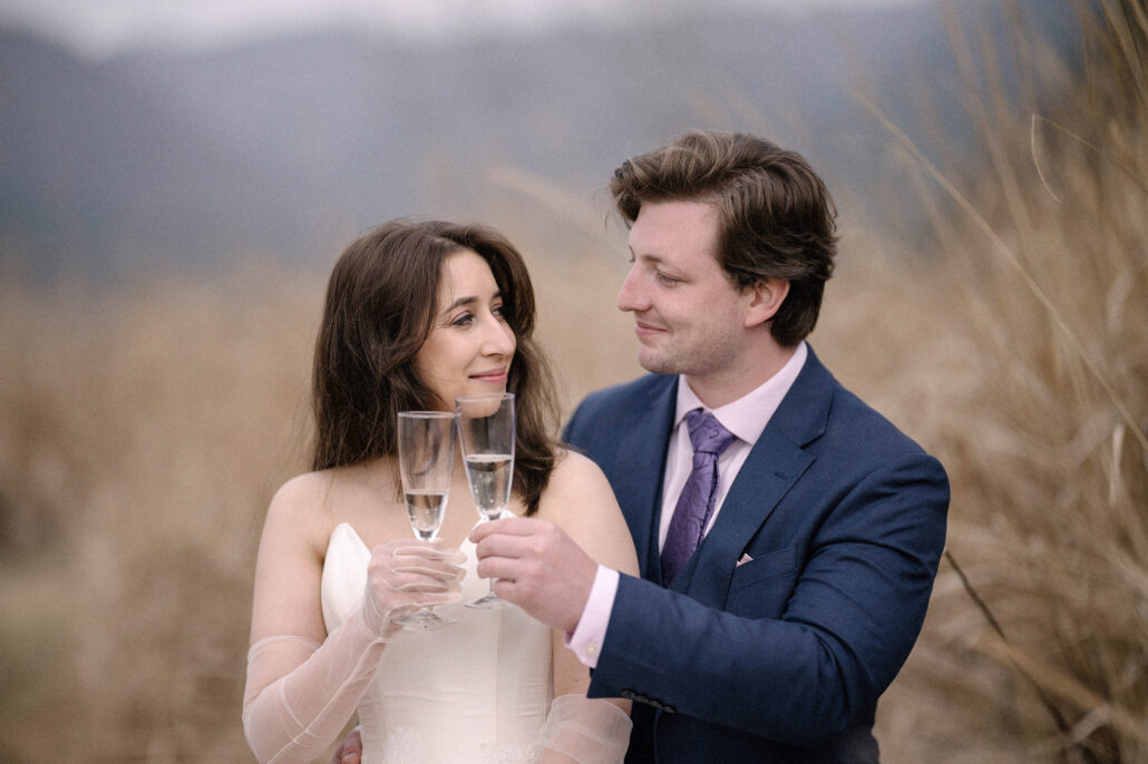 The bride and groom share a champagne toast and a long look in golden grass by Lake Kawaguchi, a Mt Fuji elopement celebration.