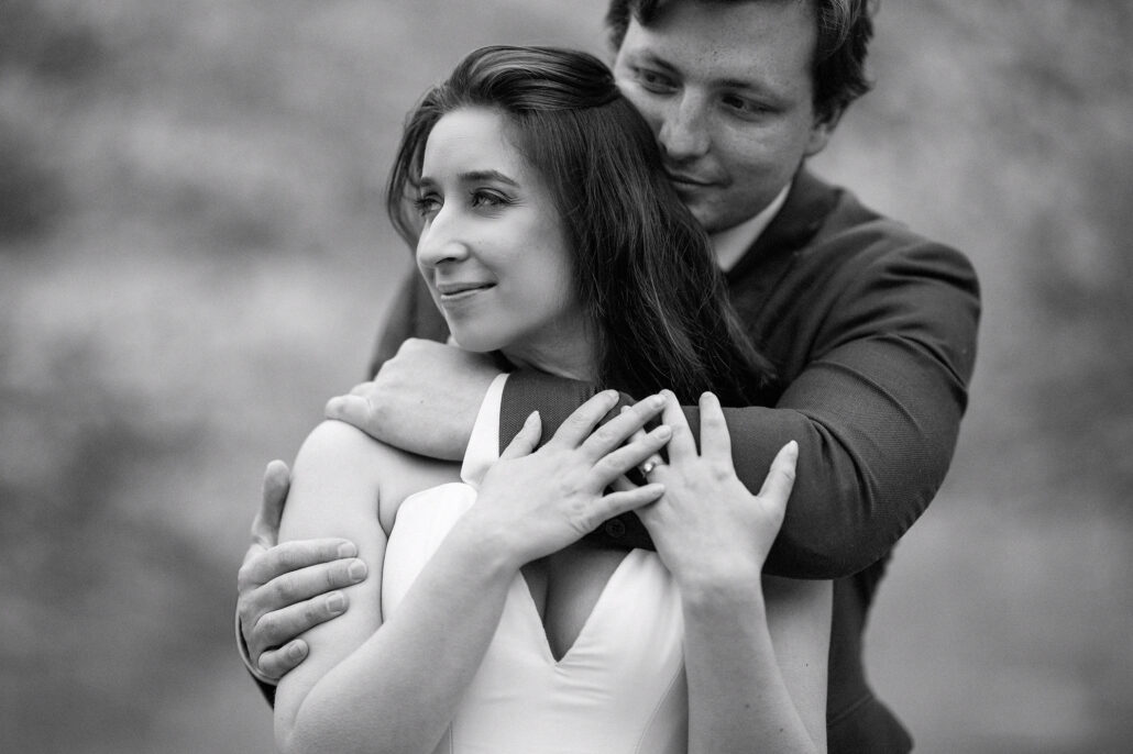 In black and white, the groom wraps his arms around the bride as she looks away and smiles, an elopement portrait in Japan in spring.