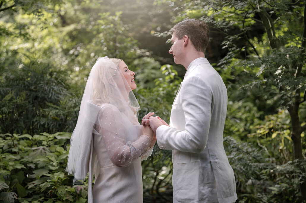 The bride and groom hold hands and share their vows under the trees at Jinya, a quiet Japanese garden elopement ceremony.