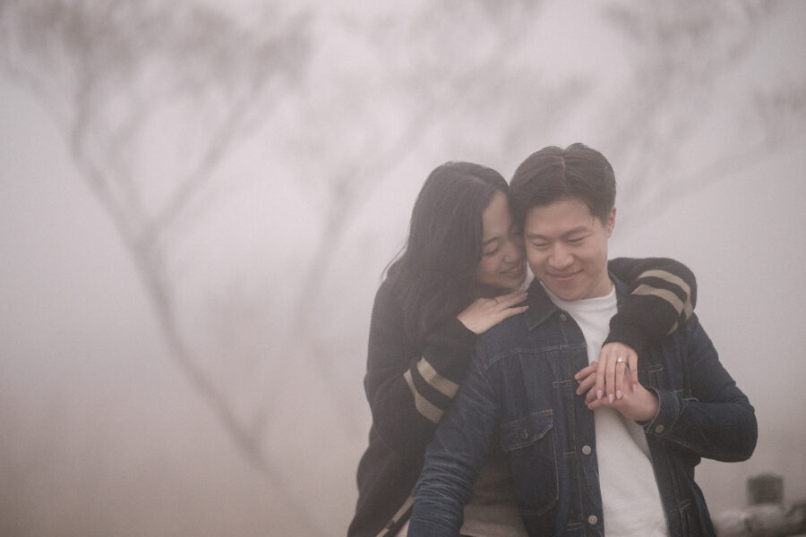 Moments after a Hakone proposal, she hugs him from behind in the spring mist, her hand on his chest showing the new ring.