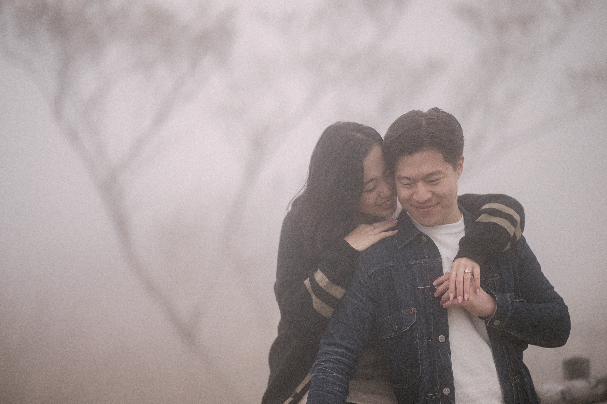 Moments after a Hakone proposal, she hugs him from behind in the spring mist, her hand on his chest showing the new ring.