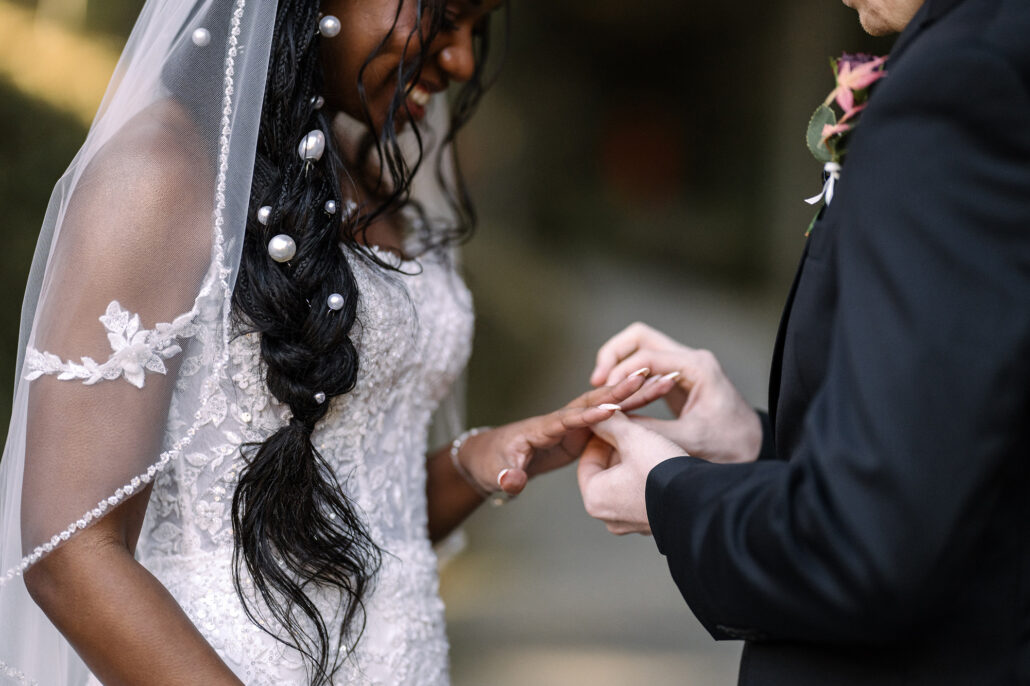 The groom slips the ring onto the bride's finger during their garden ceremony in Kyoto.
