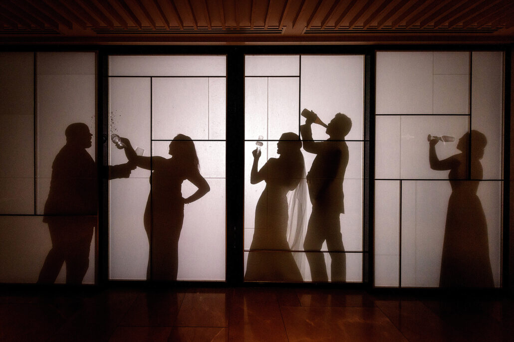 The silhouettes of the couple and their friends dance and drink behind tall paper screens at a wedding party in Kyoto.