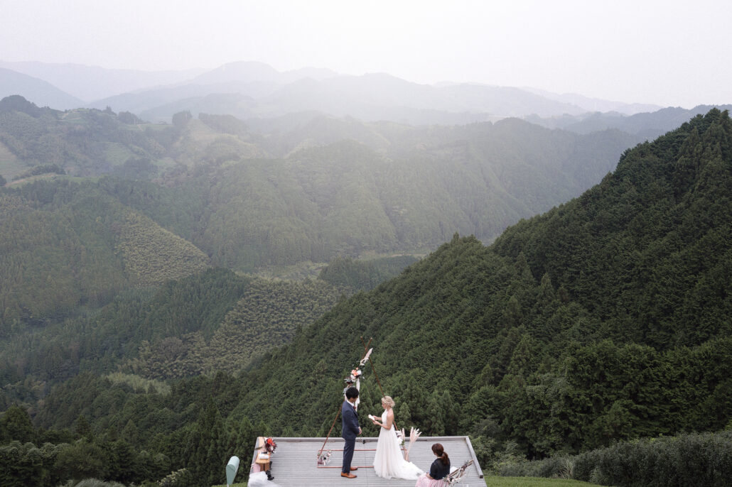 A couple marry on a terrace in a green tea field in Shizuoka, mist lying on the mountains beyond.