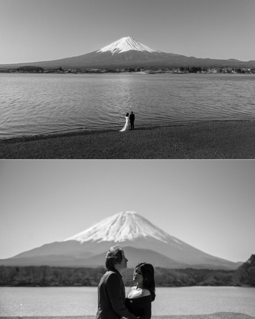 In black and white, the couple stand small on a lakeshore with Mt Fuji across the water, then face each other at the water's edge below the summit.
