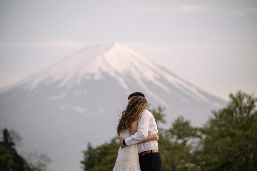 Held close in his arms, she leans into him as the snowy slopes of Mt Fuji soften into the pale evening light behind them.
