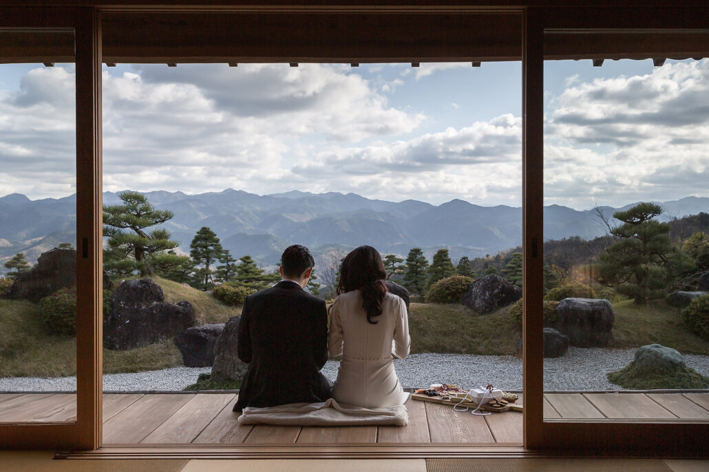 The bride and groom sit on the veranda of a private villa in the hills of Nara, looking out across a garden to a whole range of mountains.