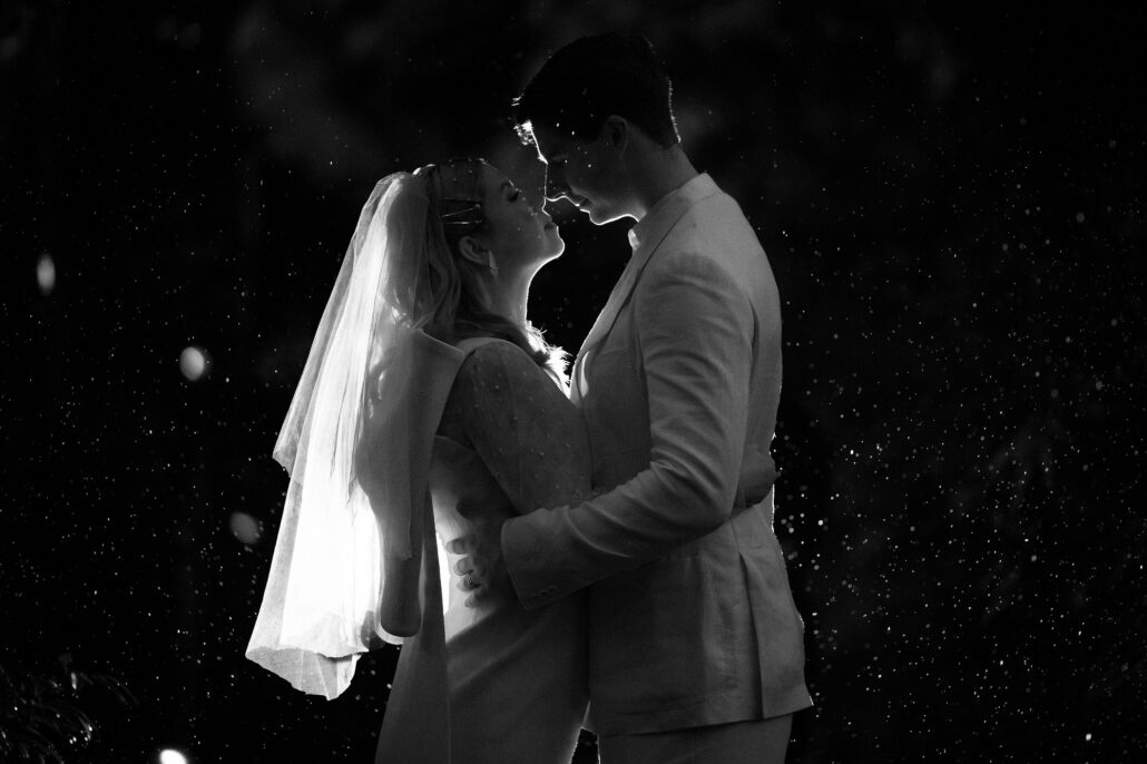 Rain catches the light around the couple as they lean in close, a black and white night portrait from an elopement in Japan.