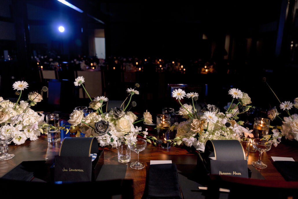 Place cards, candles and white flowers line the tables of the reception in the dark hall at Jinya.