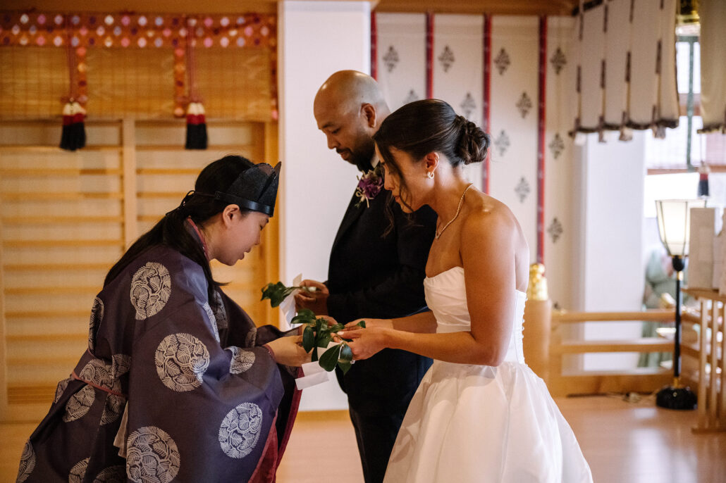 A Shinto priest hands the bride and groom a sakaki branch to offer during their wedding blessing at Naruko Tenjin Shrine in Tokyo.